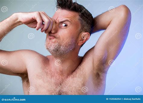 close up portrait of man smelling his armpit feeling bad odor wants