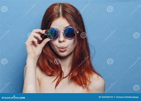 mujer pelirroja perky con lentes azules hombros desnudos posando foto