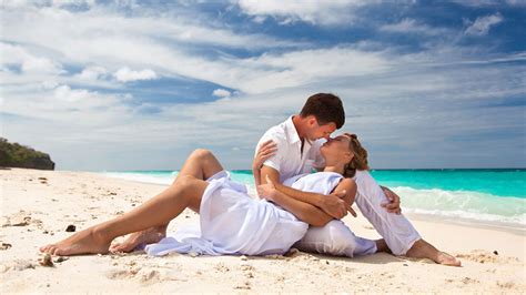 couple is wearing white dress sitting on beach sand hd couple