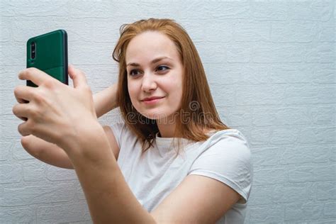Beautiful Young Woman In Casual Wear Is Making A Selfie Using A Smart