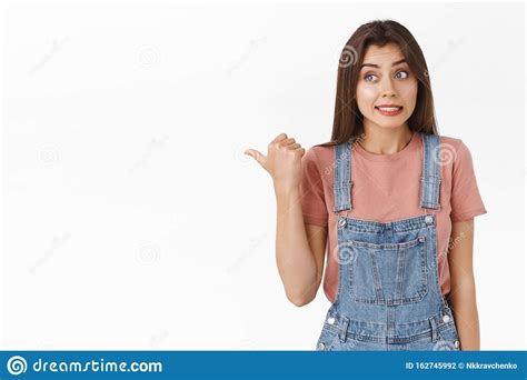 Awkward And Slightly Worried Cute Brunette Female In Overalls T Shirt