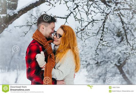 Hugging Loving Couple Is Laughing During The Snowfall In The Forest