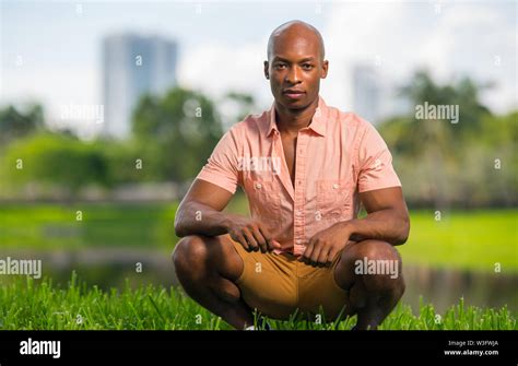 handsome man in a squat pose wearing a pink shirt and shorts african