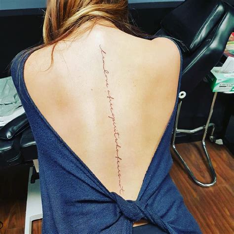the back of a woman s neck with writing on her lower back and upper back