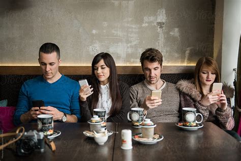 ver four friends looking at their mobile phone in a cafe del