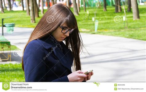 beautiful woman in glasses uses cell smartphone outdoors