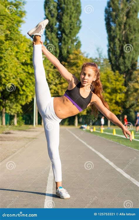 Teenage Girl Is Training At The Stadium Doing Stretching On The Stock