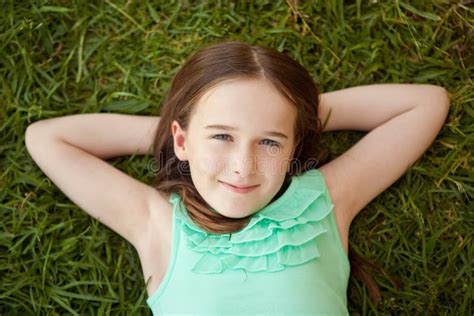 A Young Girl Is Lying On Her Back On The Grass Looking Up Stock Image