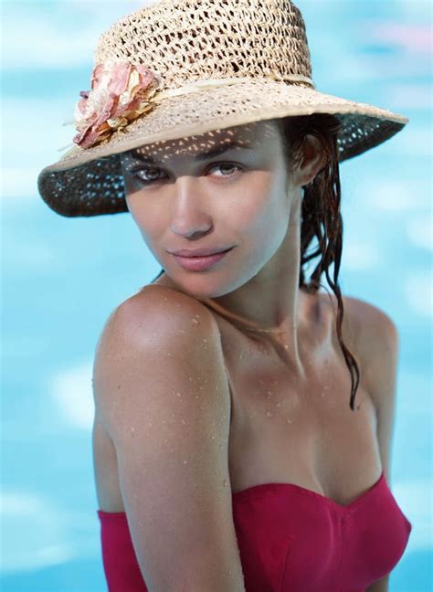 olga kurylenko outdoor portrait with pool in background wearing straw hat and red swimsuit