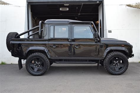 a black land rover parked in front of a garage with its doors open and