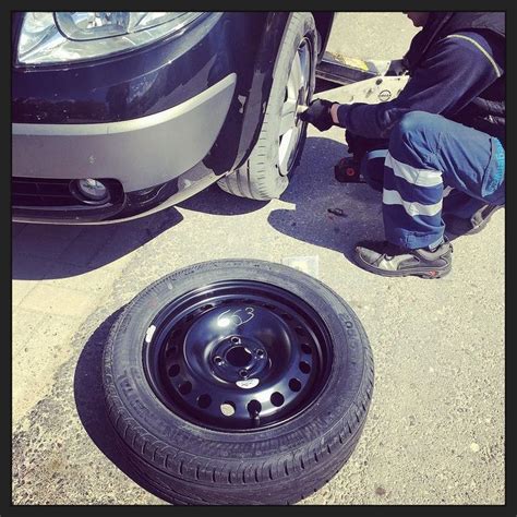 man working   tire    parked car   flat tire