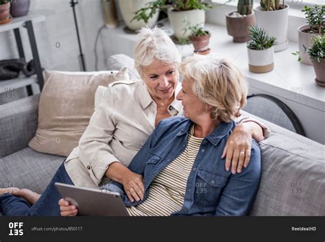 Mature Lesbian Couple Looking At Digital Tablet Together On Sofa Stock