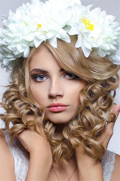 A Woman With Flowers In Her Hair Posing For The Camera And Looking At