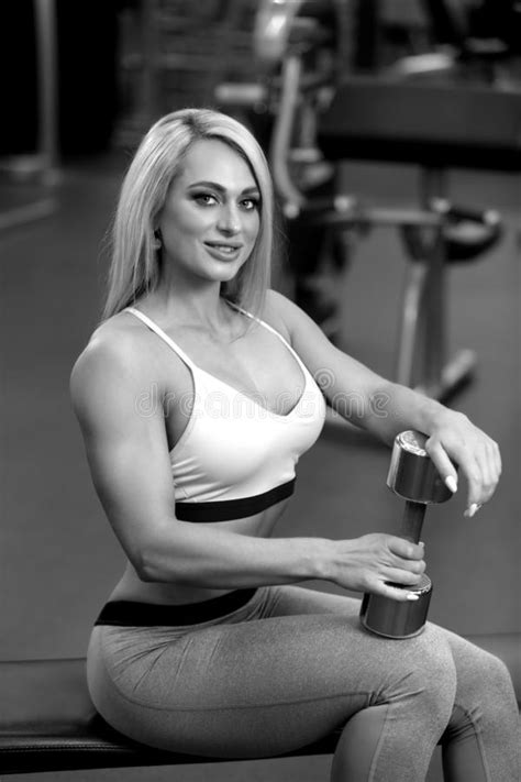 Fitness Blonde Woman Is Standing With Weight Plate In The Gym Bw Stock