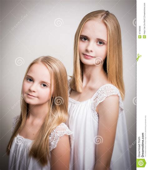 twee mooie blonde tieners kleedden zich in wit stock foto