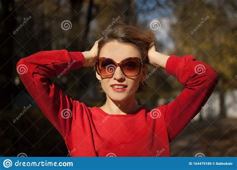 Beautiful Smiling Woman Wearing A Sunglasses And Red Sweater Is Posing