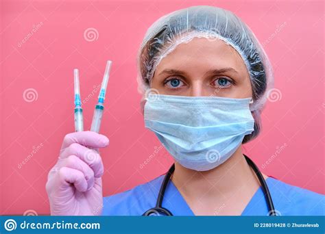Woman Doctor Holds Syringes In His Hand On A Pink Background Concept