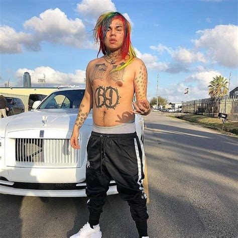 a tattooed man standing next to a white car