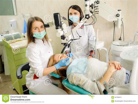 female dentist treating caries using microscope at the dentist office stock image image of