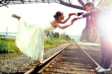 beautiful wedding couple holding hands and posing on the train tracks in the sunlight new york