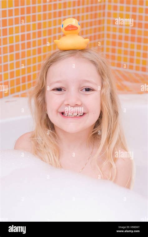 7 year old girl in der badewanne rubberduck auf dem kopf