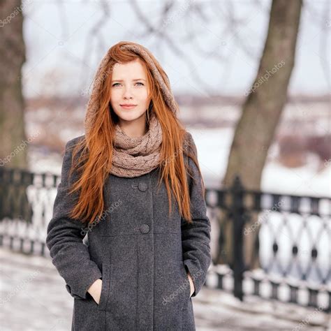 lebensstil portrait der jungen schönen rothaarige frau im mantel und schal im winter park