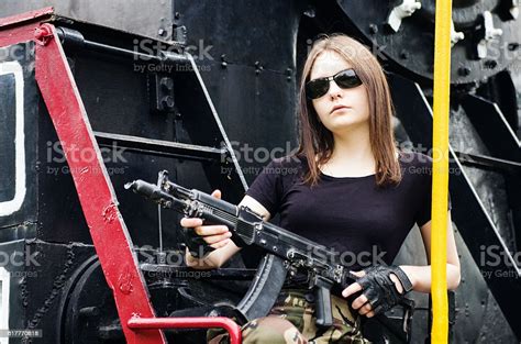 girl with gun sitting on running board of steam locomotive zdjęcia