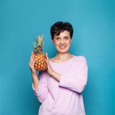 Portrait Of Attractive Short Haired Mature Woman Holding Pineapple