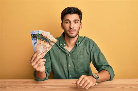 young handsome man holding canadian dollars relaxed