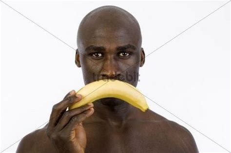 african man holding a banana in front of his mouth download people