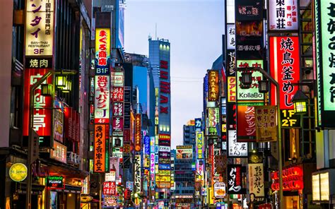 A City Street Filled With Lots Of Tall Buildings And Neon Signs On The
