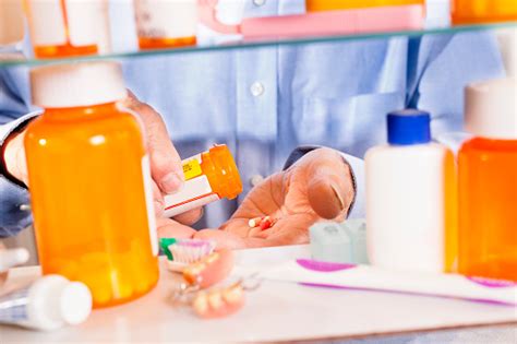 Man Taking Prescription Pills Out Of Medicine Cabinet Bottles
