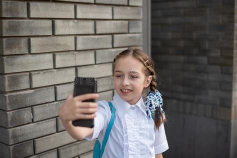 smiling beatiful preteen girl taking a selfie outdoors