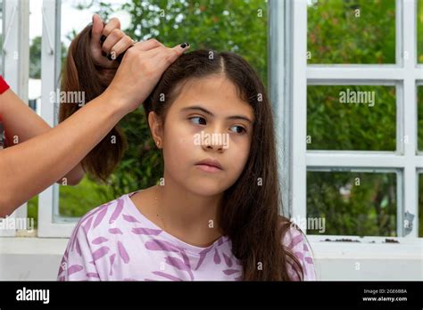 Latina Girl Sits Pensively While Having Her Hair Combed Near A Window