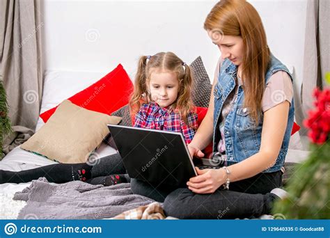 mother and daughter using laptop on bed in bedroom mom