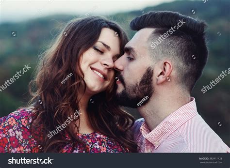 happy handsome husband and beautiful pregnant wife kissing in nature