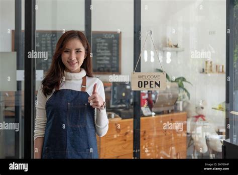 Portrait Of A Smiling Asian Entrepreneur Standing Behind Her Cafe