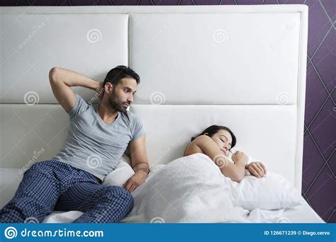 Man Trying Sexual Approach With Woman In Home Bed Stock