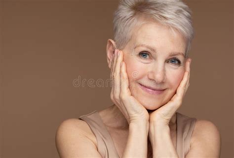 beauty portrait of mature woman smiling with hand on face stock image