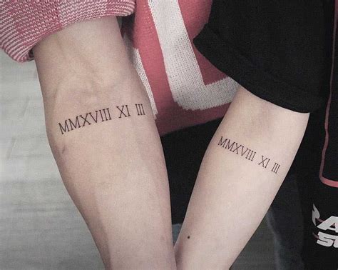 roman numerals matching wedding anniversary tattoo inked on forearms