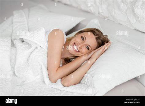 Happy Young European Blonde Woman Wake Up In Bed And Enjoys Free Time