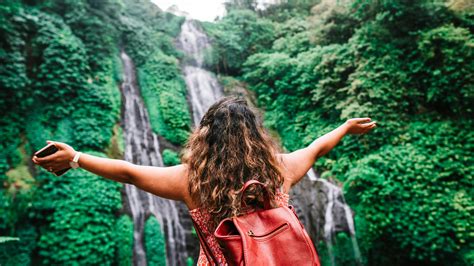 anonymous female traveler admiring amazing waterfall  stock photo