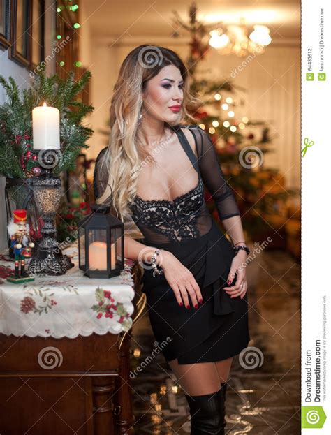 beautiful woman in elegant black dress with xmas tree in background portrait of fashionable