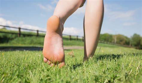 womans feet walking away on grass on a sunny day in the countryside