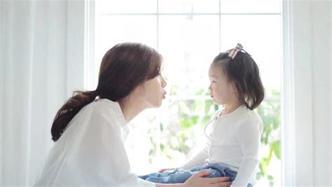 beautiful asian mom and her cute daughter kissing with
