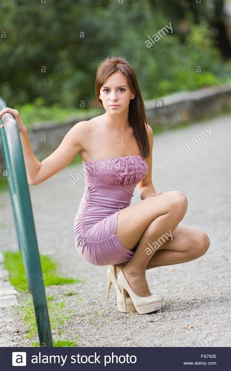 Teen Girl Pretty In Fanciful Minidress Squatting In Park