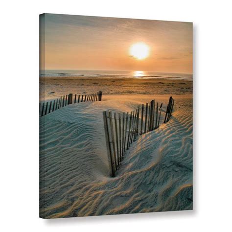 the sun is setting behind a fence in the sand at the beach canvas wall