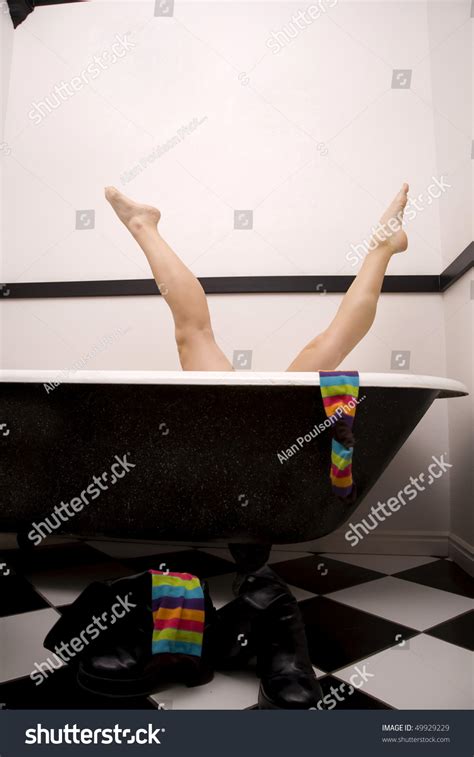 a woman in her tub playing around putting her legs up in the air in the splits with her