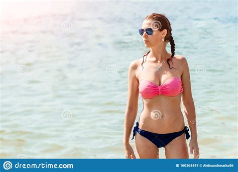 jonge mooie meid in een badpak en een zonnebril staat op
