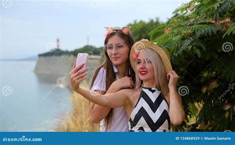 Two Positive Girls Blonde In Hat And Brunette With Glasses Fooling